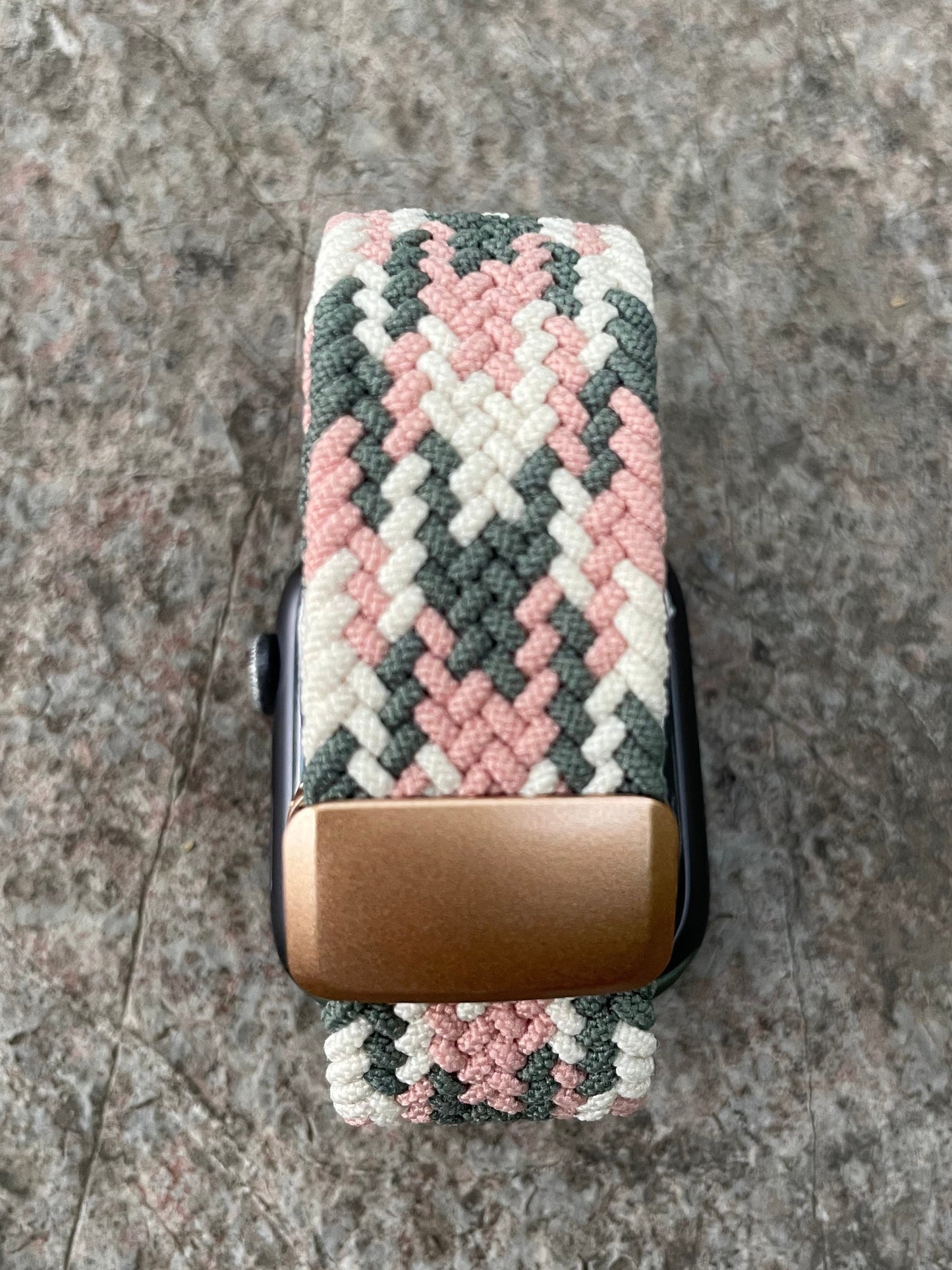 Apple watch band with a pink and grey pattern on a concrete surface